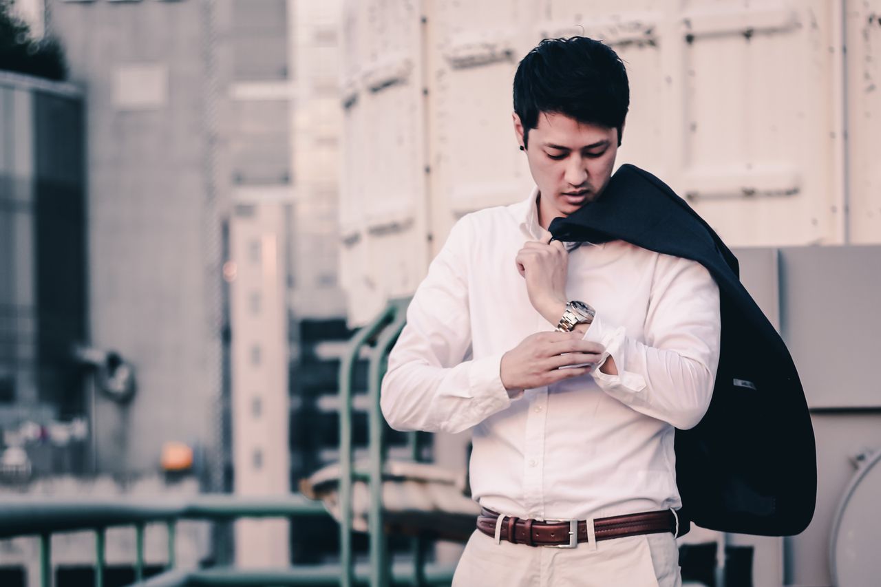 our-mission-01 A fashionable Asian man adjusts his suit jacket in a modern cityscape in Seoul.
